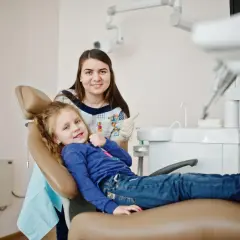 Uśmiechnięta dziewczynka w gabinecie stomatologicznym w Krakowie. Stomatolog dziecięcy w Krakowie - ranking polecanych placówek.