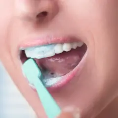 Usta z pianą i szczoteczką do zębów. Codzienne mycie zębów to podstawa higieny.