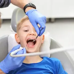 Chłopiec uśmiecha się szeroko, gdy dentysta wykonuje fluoryzację w szkole, dbając o zdrowe zęby.