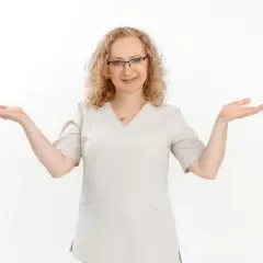 Kobieta w okularach i jasnym uniformie medycznym z otwartymi dłońmi.