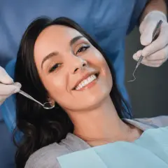 Uśmiechnięta pacjentka u dentysty, która mimo narzędzi nie wykazuje odruch wymiotny.