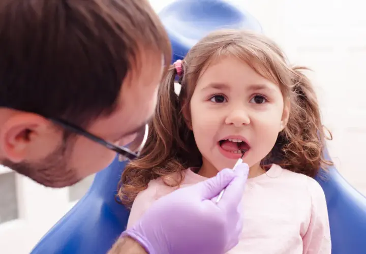 Mała dziewczynka u dentysty, który wykonuje lapisowanie zębów.
