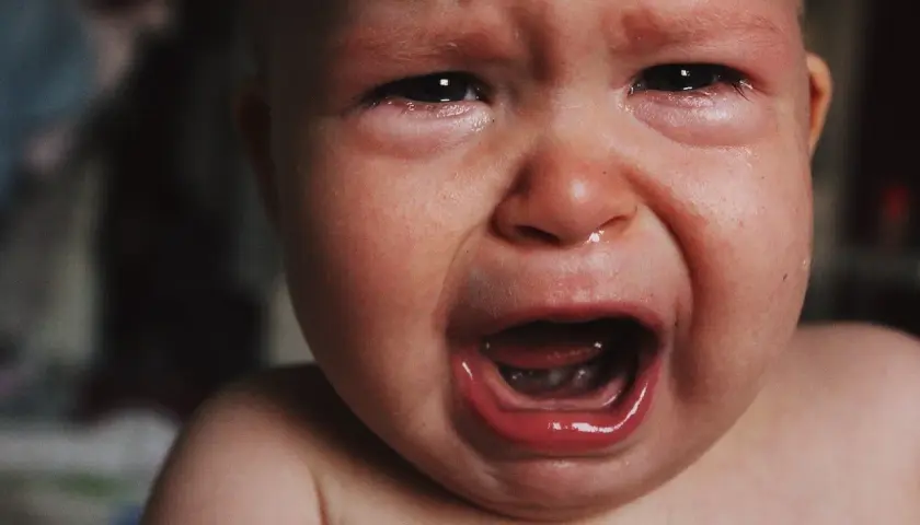 Malutkie dziecko płacze, ma zaczerwienione oczy i mokry nosek. To pewnie katar przy ząbkowaniu, który sprawia mu ból.