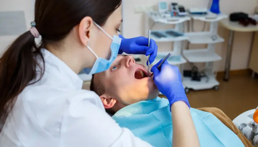 Dentystka bada zęby pacjenta. Zastanawiasz się, na ile dentysta może wystawić L4? Zależy to od stanu zdrowia pacjenta i zaleceń lekarskich.