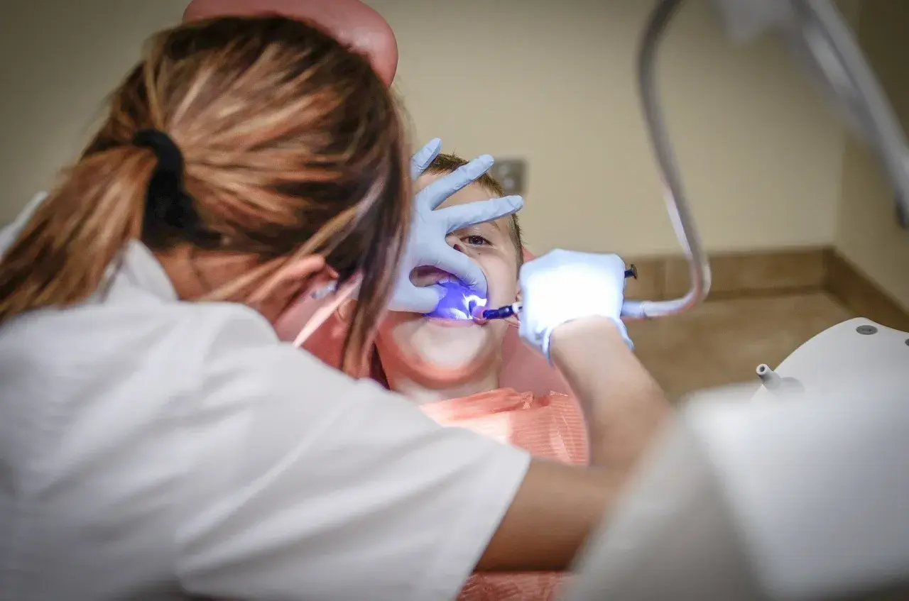 Dziecko u dentysty we Wrocławiu. Zabieg stomatologiczny z użyciem lampy polimeryzacyjnej. Najlepsze kliniki stomatologiczne we Wrocławiu.