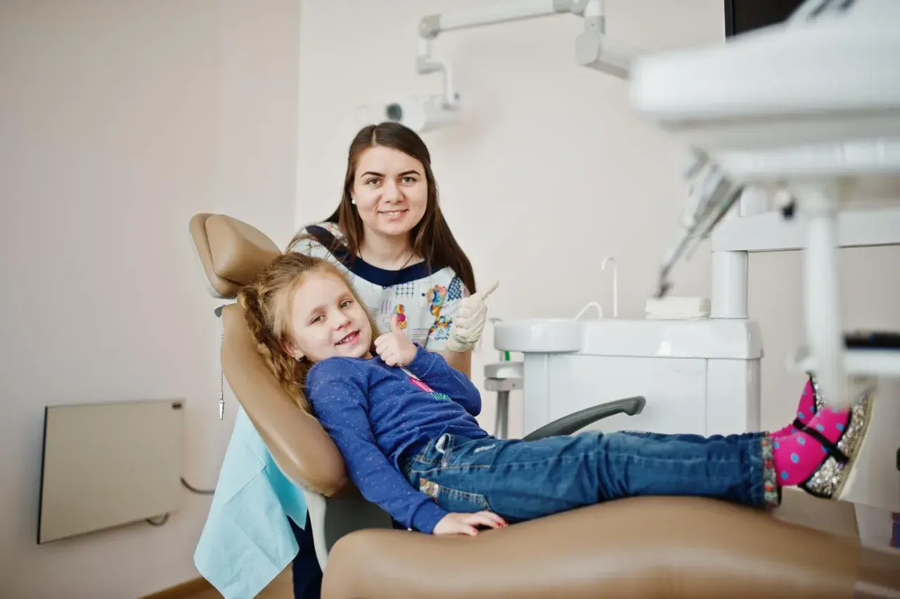 Uśmiechnięta dziewczynka w gabinecie stomatologicznym w Krakowie. Stomatolog dziecięcy w Krakowie - ranking polecanych placówek.