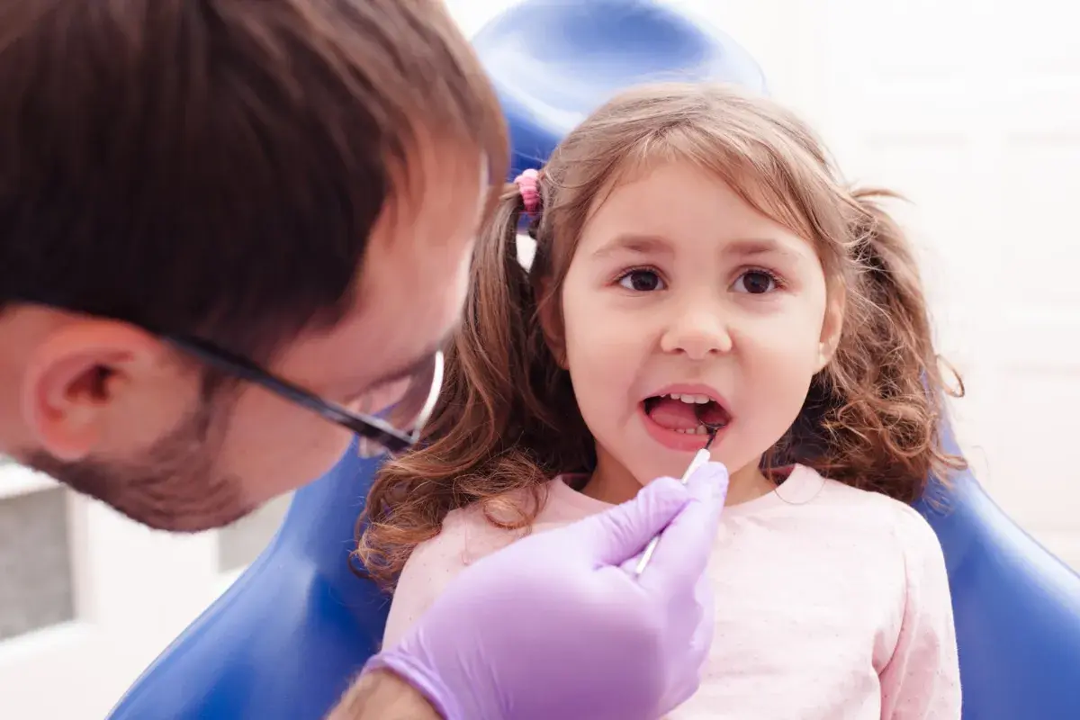 Mała dziewczynka u dentysty, który wykonuje lapisowanie zębów.