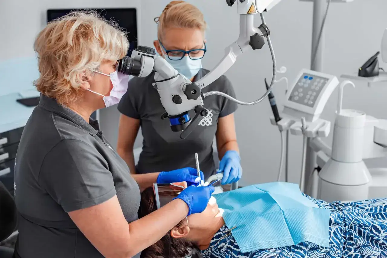 Dentystka pod mikroskopem bada przyczynę bólu zęba przy nagryzaniu.