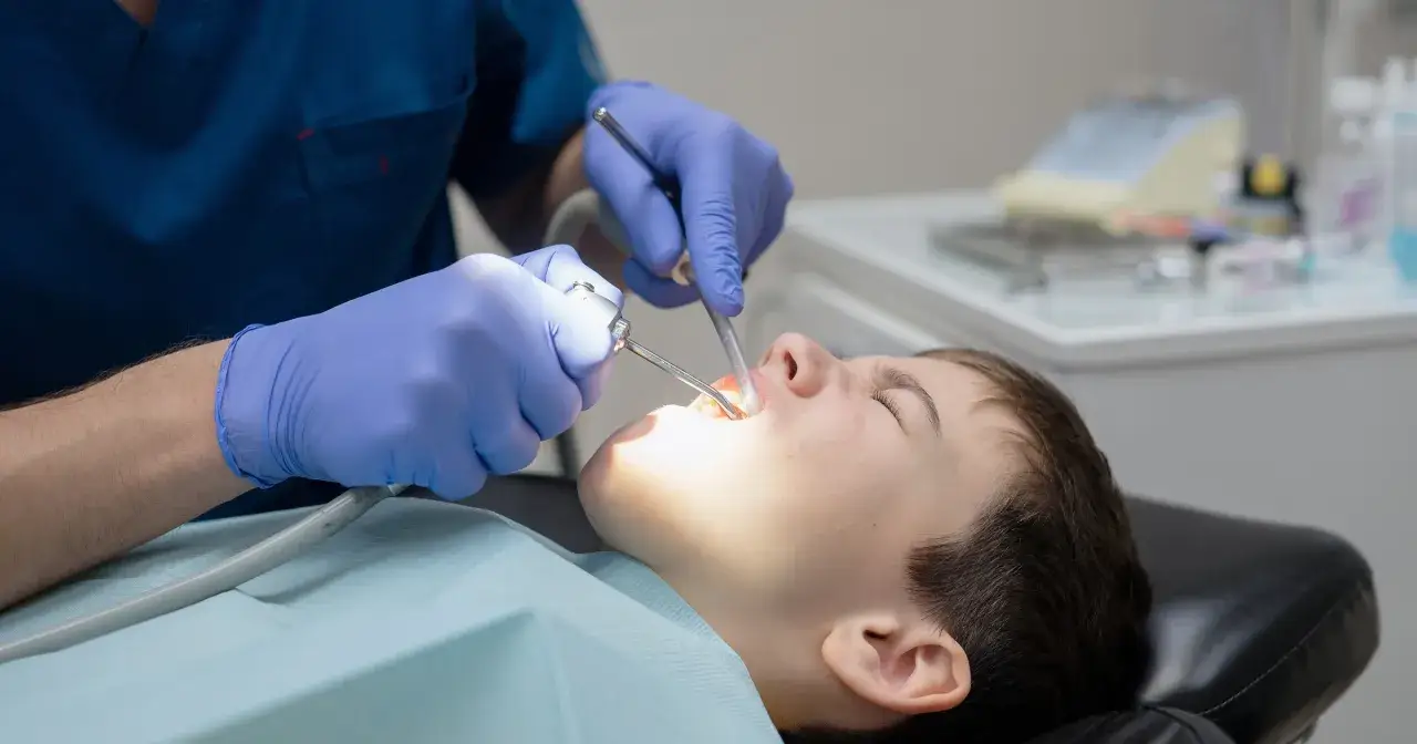Chłopiec u dentysty, który wykonuje zabieg. Zastanawiasz się, ile kosztuje znieczulenie u dentysty?