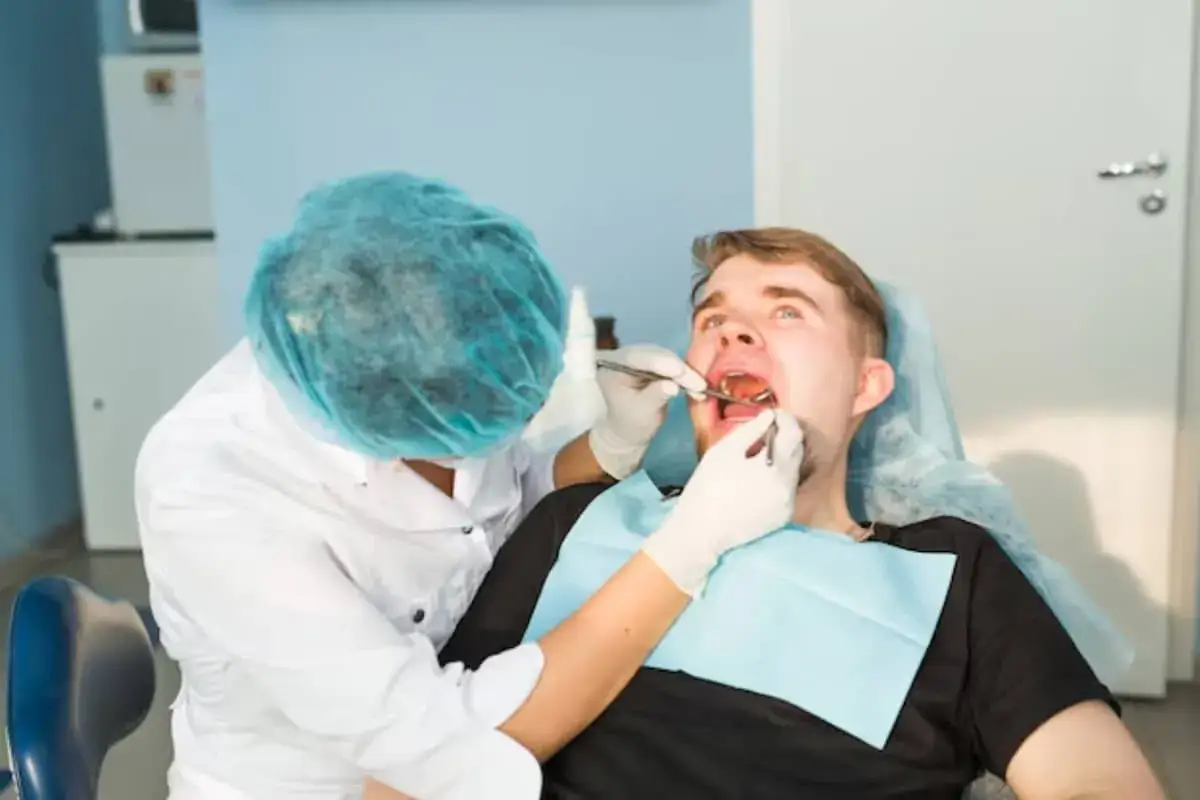 Dentysta bada pacjenta z krwawiącymi dziąsłami, podejrzewając nowotwór.