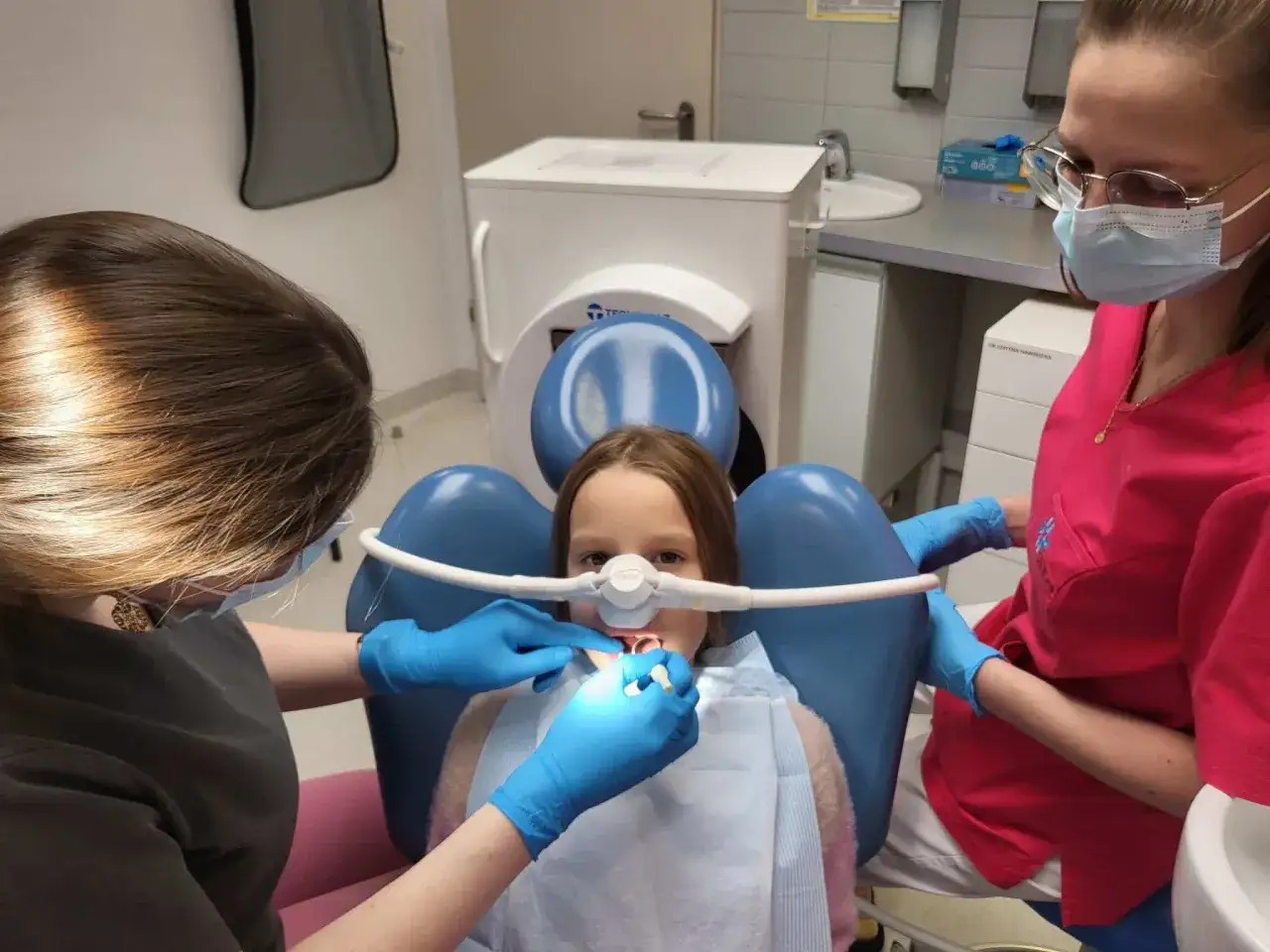 Dziecko uśmiecha się, czując lekki oddech gazu rozweselającego podczas wizyty u dentysty.