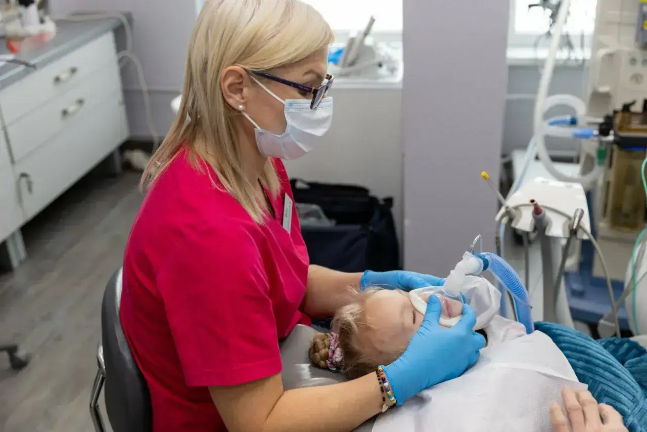 Dentystka zakłada dziecku maskę do znieczulenia. Warto sprawdzić, ile kosztuje znieczulenie u dentysty na NFZ, by uniknąć niespodzianek.