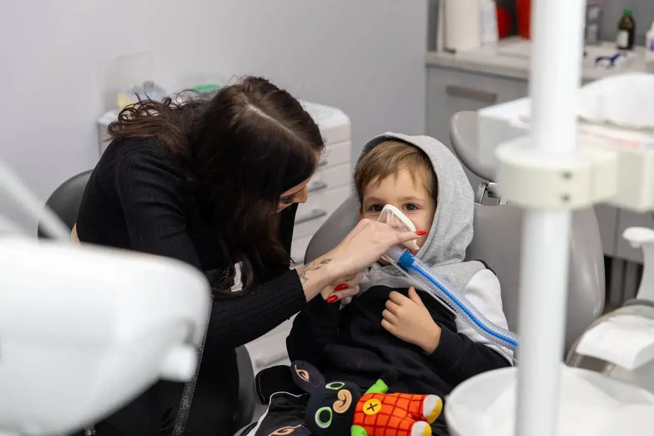 Dziecko w masce tlenowej u dentysty. Rodzic uspokaja, by uniknąć potencjalnych lidokaina skutki uboczne.