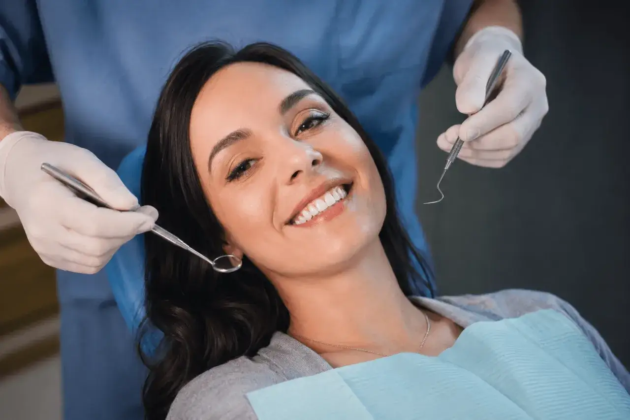 Uśmiechnięta pacjentka u dentysty, która mimo narzędzi nie wykazuje odruch wymiotny.