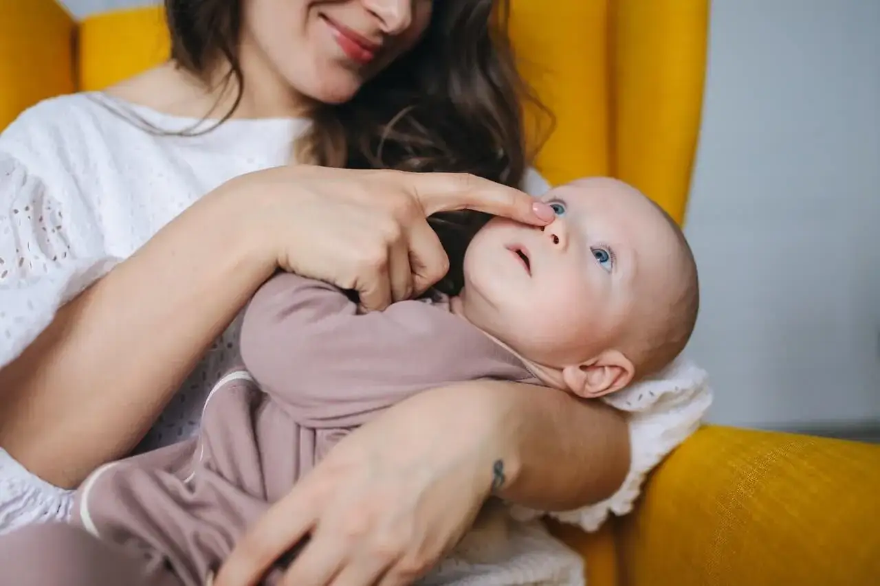 Mama delikatnie dotyka noska niemowlaka, który może mieć katar przy ząbkowaniu.