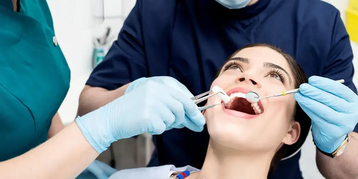 Pacjent po wizycie u dentysty, dłoń na policzku, zmartwiona twarz, dentysta udziela wskazówek
